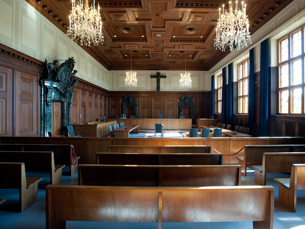 Blick in den historischen Saal 600 des Memoriums Nürnberger Prozesse mit Holzvertäfelung, Kronleuchtern und Holzbänken.