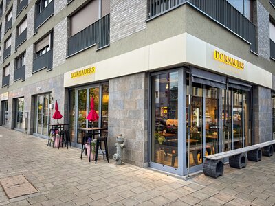 Gebäudeansicht und Eingang zu DORNAUERS in einem neugebauten Wohn- und Geschäftshaus. Moderne optik in grau gehalten. Große Fenster, die einen Blick in den Verkaufsraum bieten.