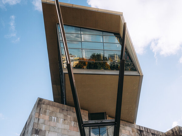 Blick von unten auf den Eingang des Dokumentationszentrums Reichsparteitagsgelände mit markantem, überhängendem Glasbau.