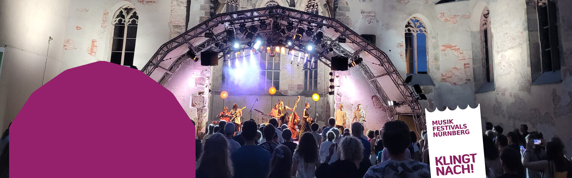 Eine Band spielt nachts auf einer blau beleuchteten Bühne in der geschichtsträchtigen Ruine der Katharinenkirche während des Katharinen Open Airs. Im Vordergrund feiert das Publikum vor der Kulisse der angestrahlten Sandsteinmauern.