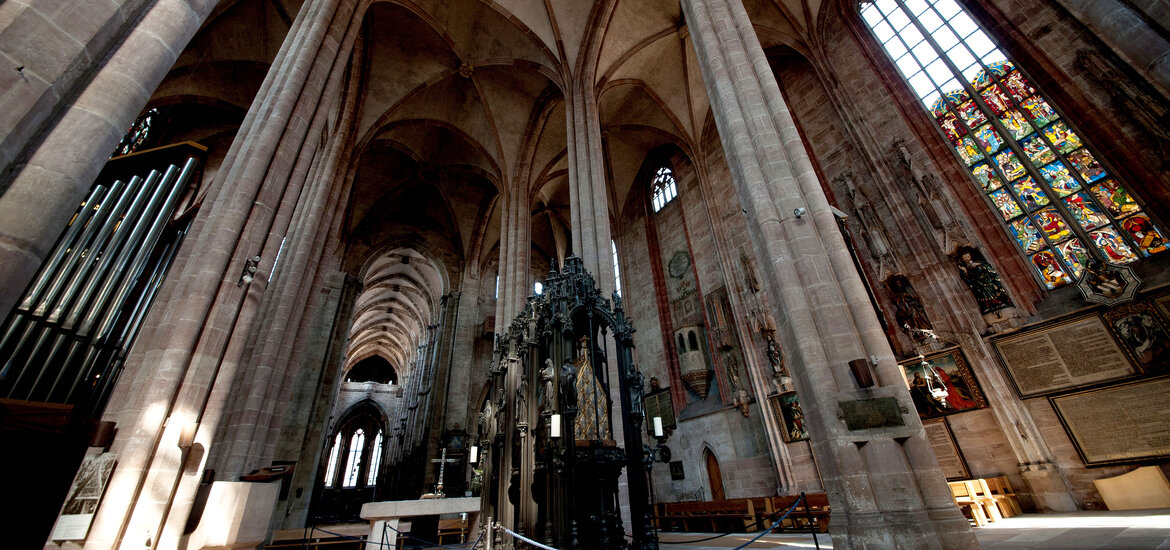 Innenraum der Sebalduskirche Nürnberg mit hohen gotischen Säulen und einem Grab in der Mitte