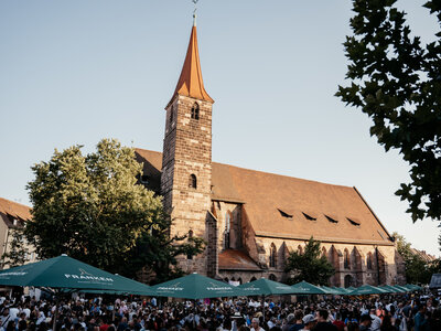 Menschenmenge unter grünen Sonnenschirmen vor der Jakobskirche beim Weinfest in Nürnberg bei Tageslicht