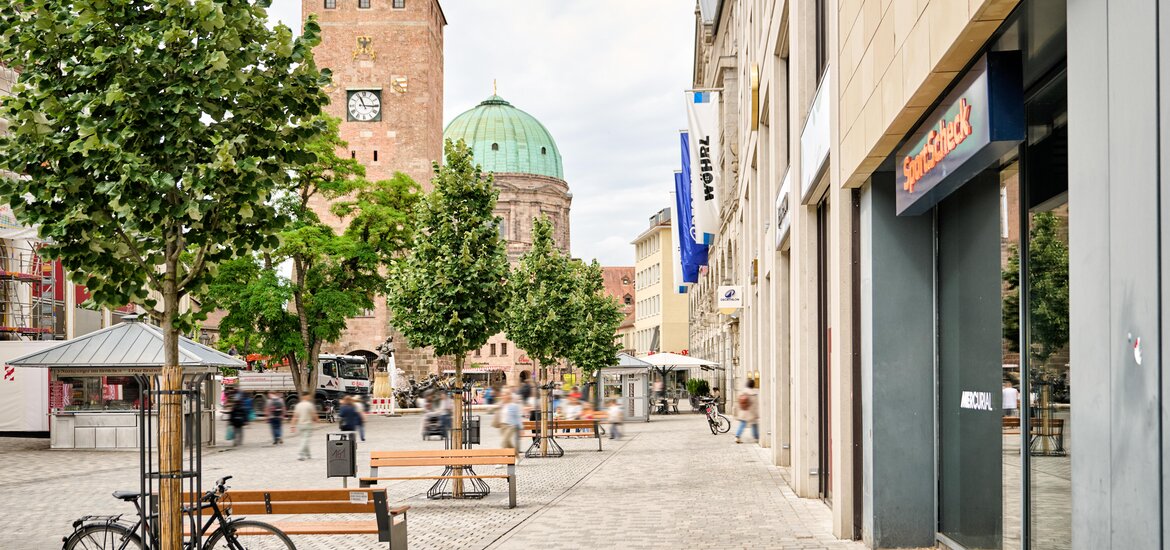 Fußgängerzone mit Bänken, Bäumen und Fahrrad vor Gebäuden am Ludwigsplatz in Nürnberg
