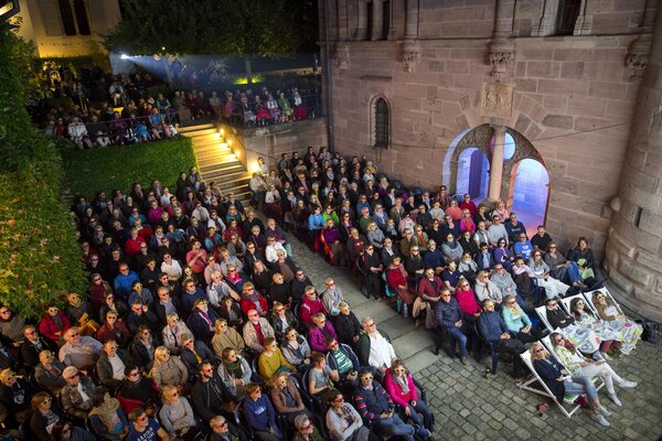 Bei dieser nächtlichen Freiluftkino-Veranstaltung im geschichtsträchtigen Innenhof des Tucherschlosses trägt das dicht gedrängt sitzende Publikum gelbe 3D-Brillen für eine Filmvorführung.
