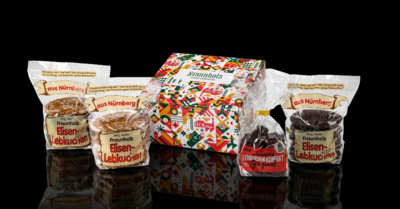 Mehrere Packungen Nürnberger Elisenlebkuchen der Marke Gebr. Fraunholz in unterschiedlichen Verpackungen vor schwarzem Hintergrund
