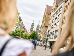 Blick durch zwei Personen auf die belebte Karolinenstraße in Nürnberg und der Lorenzkirche im Hintergrund