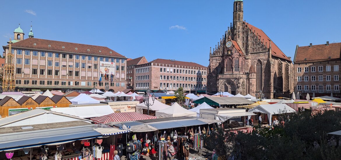 Blick auf den Herbstmarkt in Nürnberg mit zahlreichen Marktständen vor der Frauenkirche  bei klarem Himmel