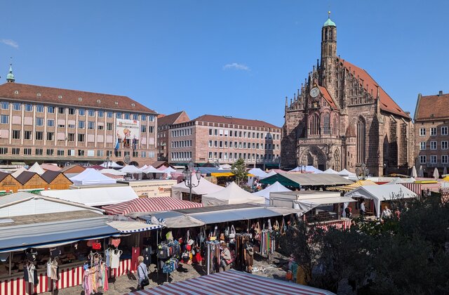 Blick auf den Herbstmarkt in Nürnberg mit zahlreichen Marktständen vor der Frauenkirche  bei klarem Himmel