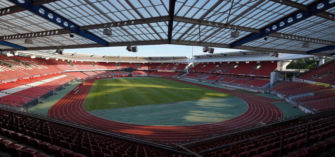 Blick auf das Max-Morlock-Stadion mit grünem Spielfeld und leeren roten Sitzreihen unter einem teilweise offenen Dach