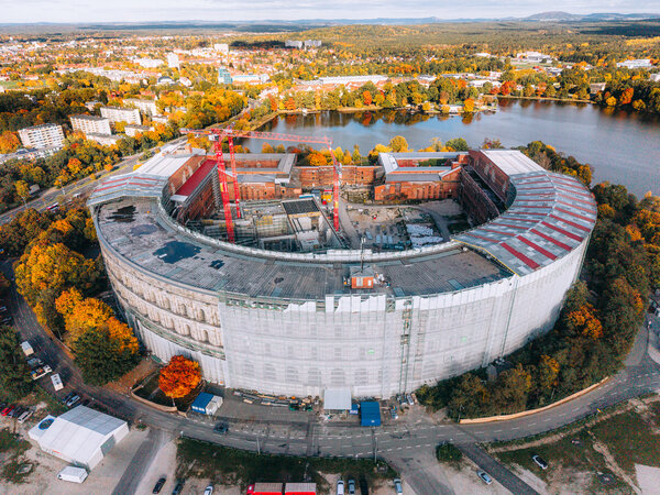 Luftaufnahme der halbrunden Kongresshalle Nürnberg mit Baustellenkränen und umgebendem herbstlich gefärbtem Baumbestand am ehemaligen Reichsparteitagsgelände.