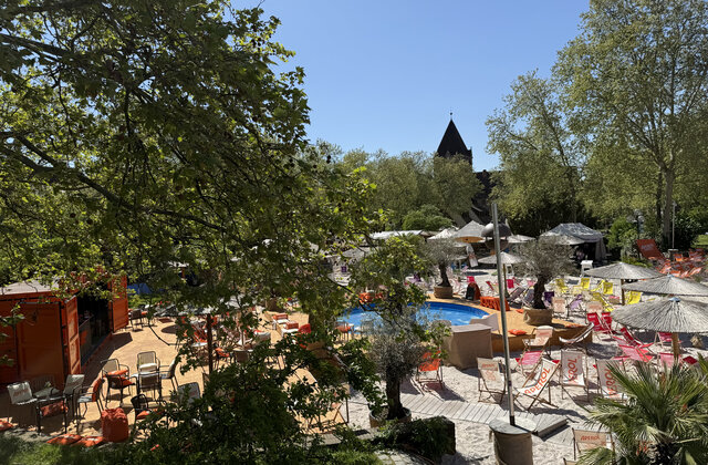 Sommerinsel Nürnberg mit Pool, Liegestühlen, Sonnenschirmen, Sand und Bäumen unter klarem Himmel