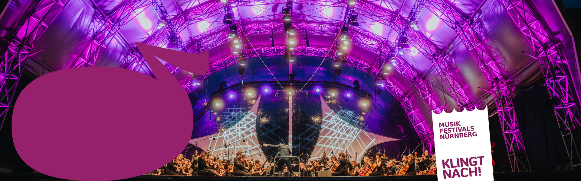 Ein Dirigent leitet ein Orchester auf einer großen Open-Air-Bühne im Nürnberger Luitpoldhain vor einer riesigen Menschenmenge auf der angrenzenden Liegewiese.