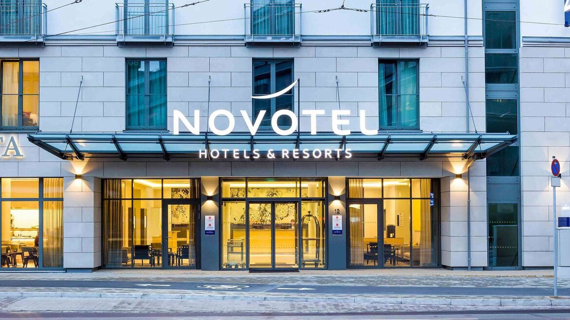 Fassade des Novotel Hotels mit großem Schriftzug und verglaster Eingangstür in einem mehrstöckigen Gebäude