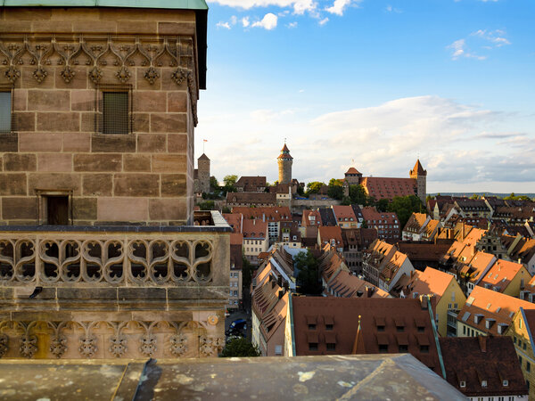 Vom detailreich verzierten Sandsteinturm der Sebalduskirche bietet sich ein weiter Blick über die rötlichen Ziegeldächer der Nürnberger Altstadt bis hin zur thronenden Kaiserburg am Horizont.