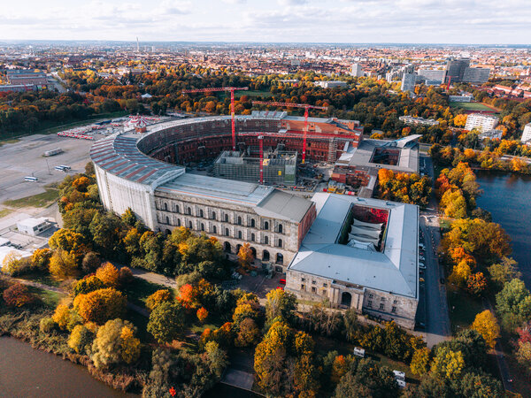 Luftaufnahme der Kongresshalle Nürnberg auf dem ehemaligen Reichsparteitagsgelände mit Baustellenkränen im Innenhof und herbstlich gefärbtem Baumbestand.