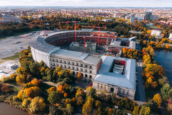 Luftaufnahme der Kongresshalle Nürnberg auf dem ehemaligen Reichsparteitagsgelände mit Baustellenkränen im Innenhof und herbstlich gefärbtem Baumbestand.