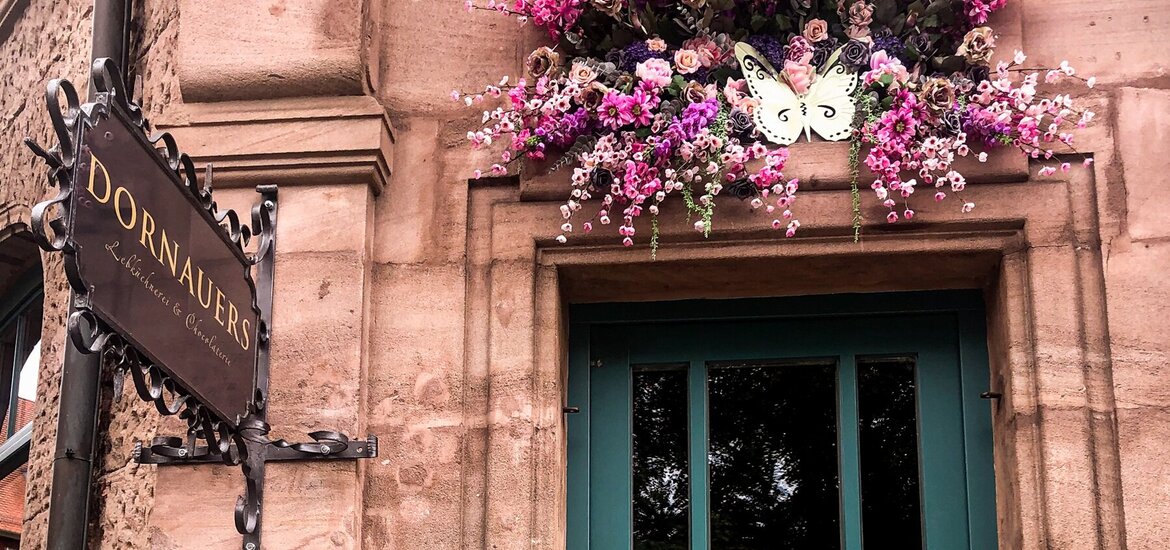 Zu sehen ist die türkise Eingangstür eines Sandstandhauses zu Dornauers Ladengeschäft